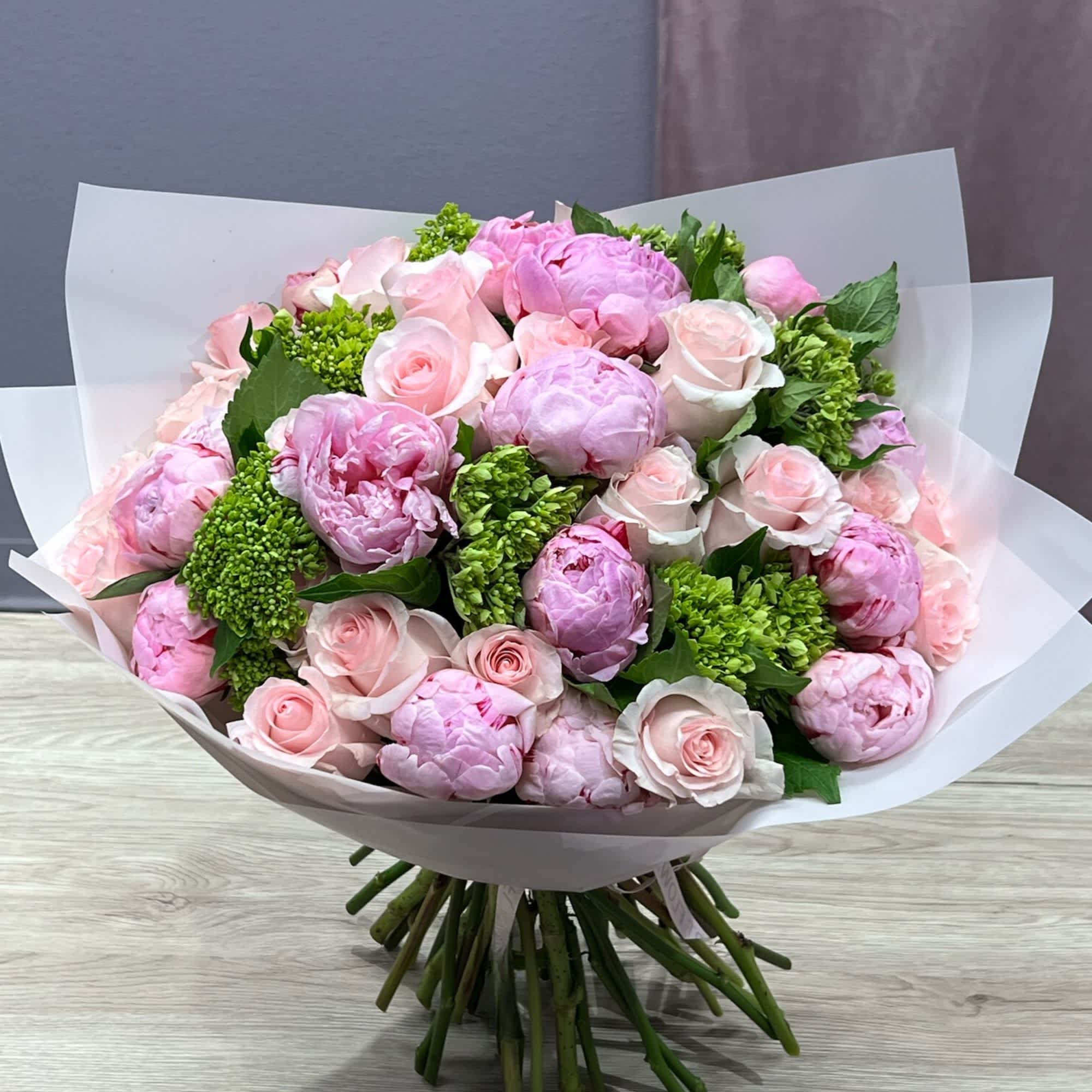 Bouquet of pink peonies and pale pink roses wrapped in white paper