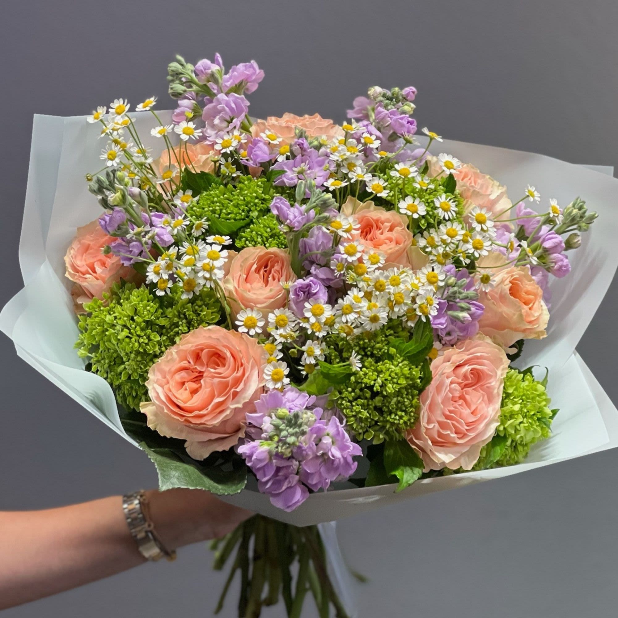 Bouquet of peach roses, purple flowers, and white daisies