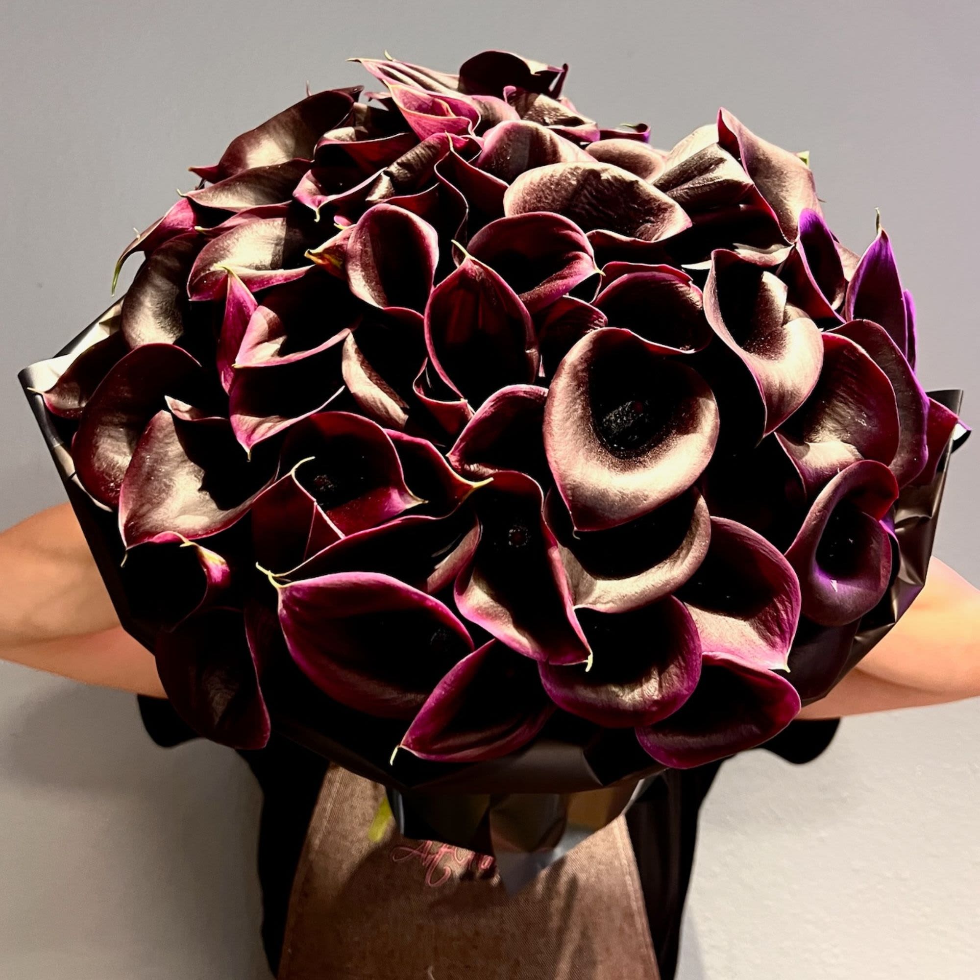 Bouquet of dark burgundy calla lilies wrapped in paper
