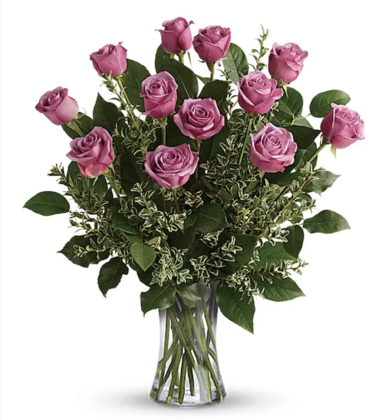 Pink roses arranged in a clear glass vase with mixed greenery