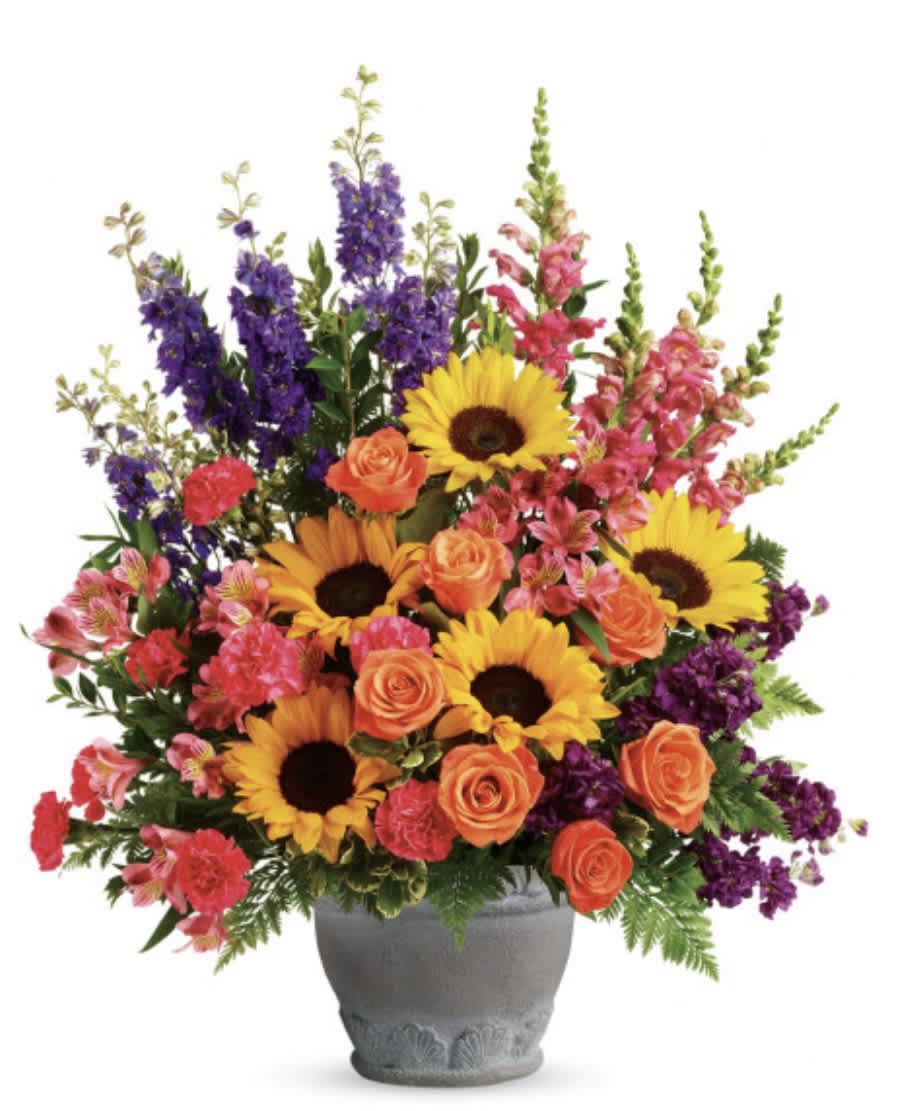 Mixed bouquet with sunflowers, orange roses, and purple spikes in a gray vase