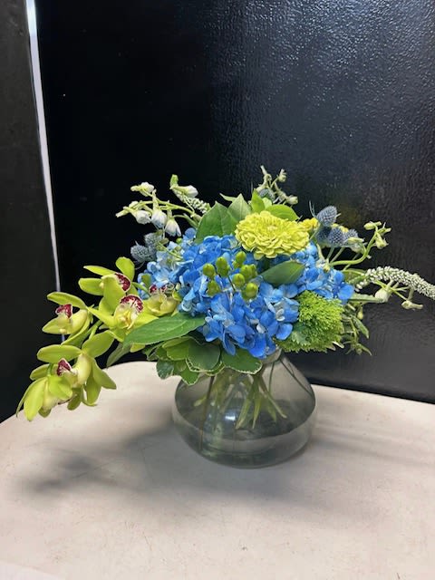 Blue hydrangeas and green orchids in a glass vase