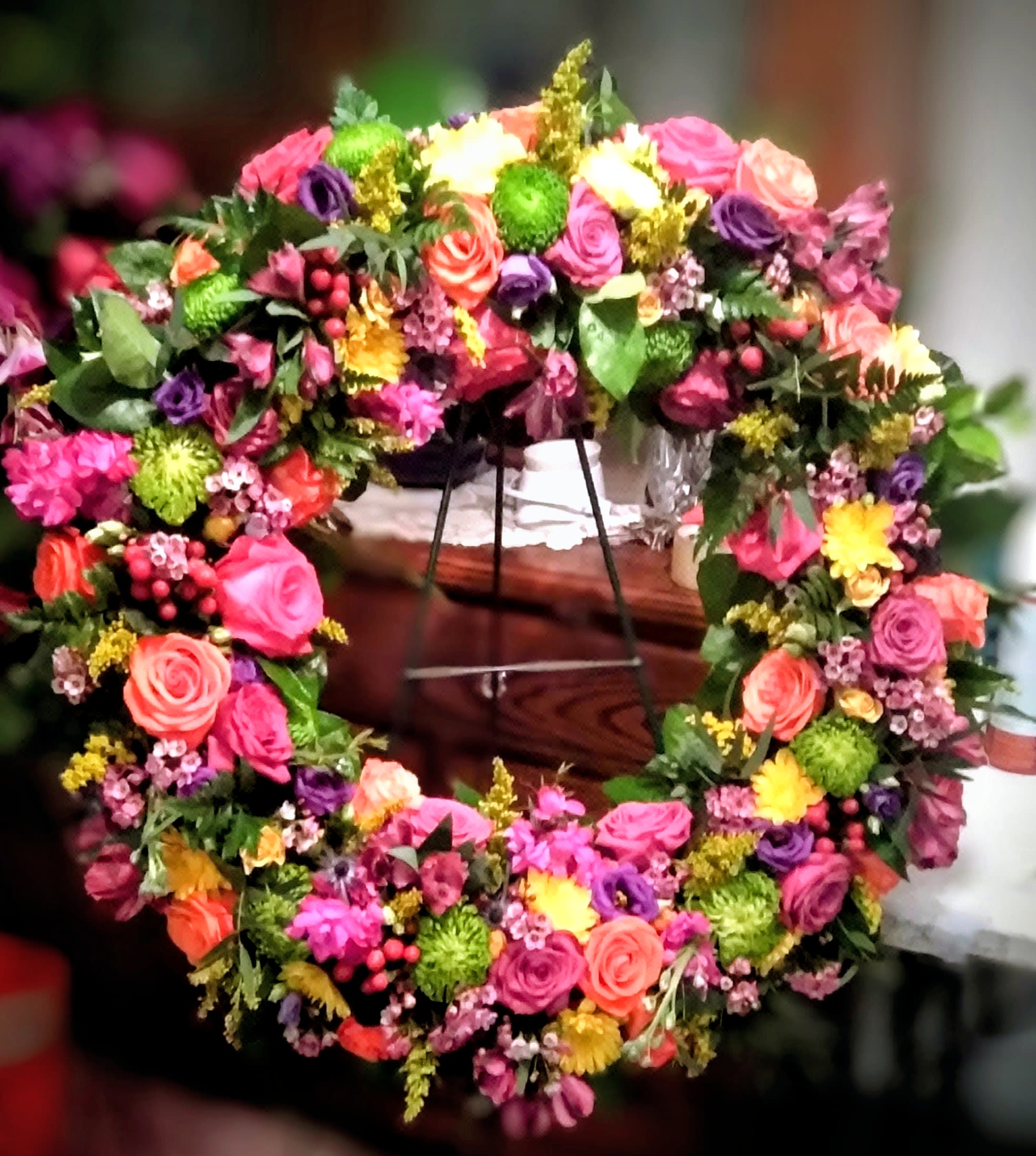 Colorful floral wreath with roses and mixed blooms on a stand