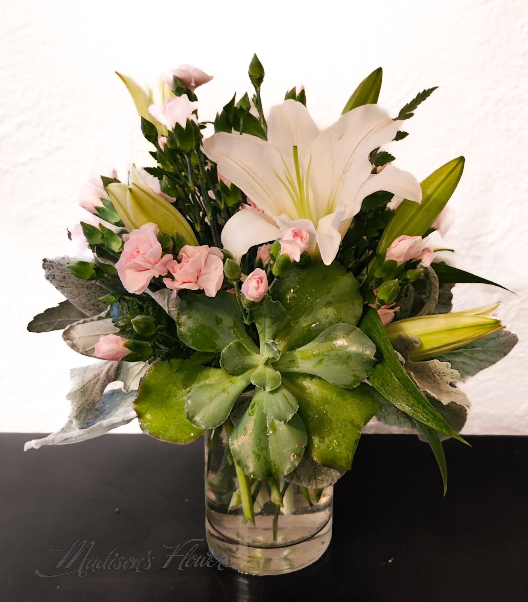 Pink carnations and white lilies arranged in a clear glass vase