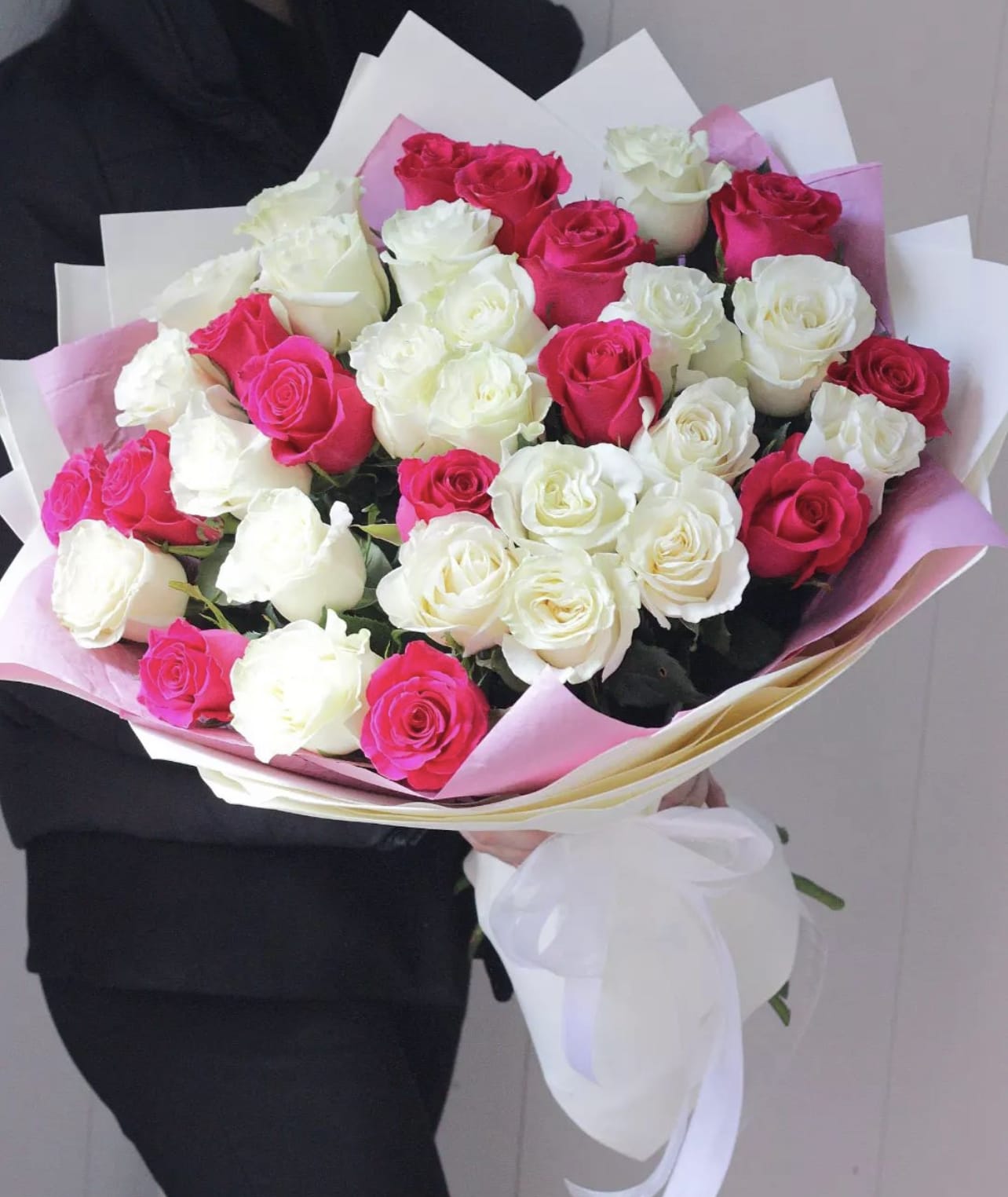 Bouquet of pink and white roses wrapped in pastel paper