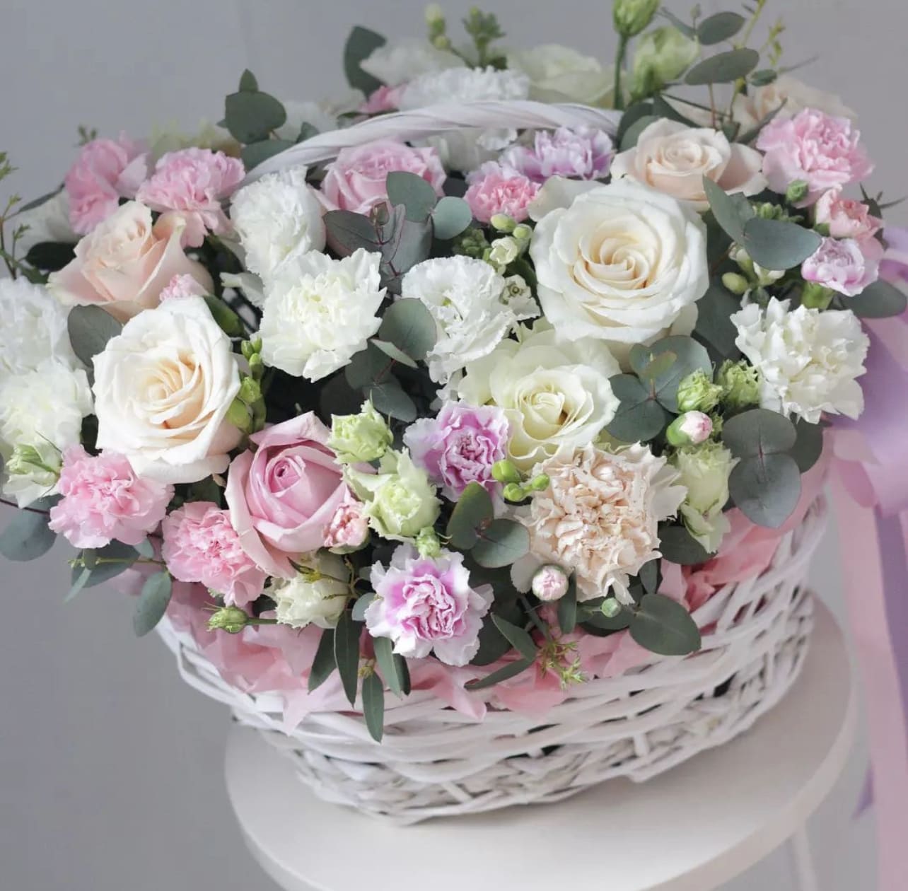 Pink and white roses with carnations in a white basket