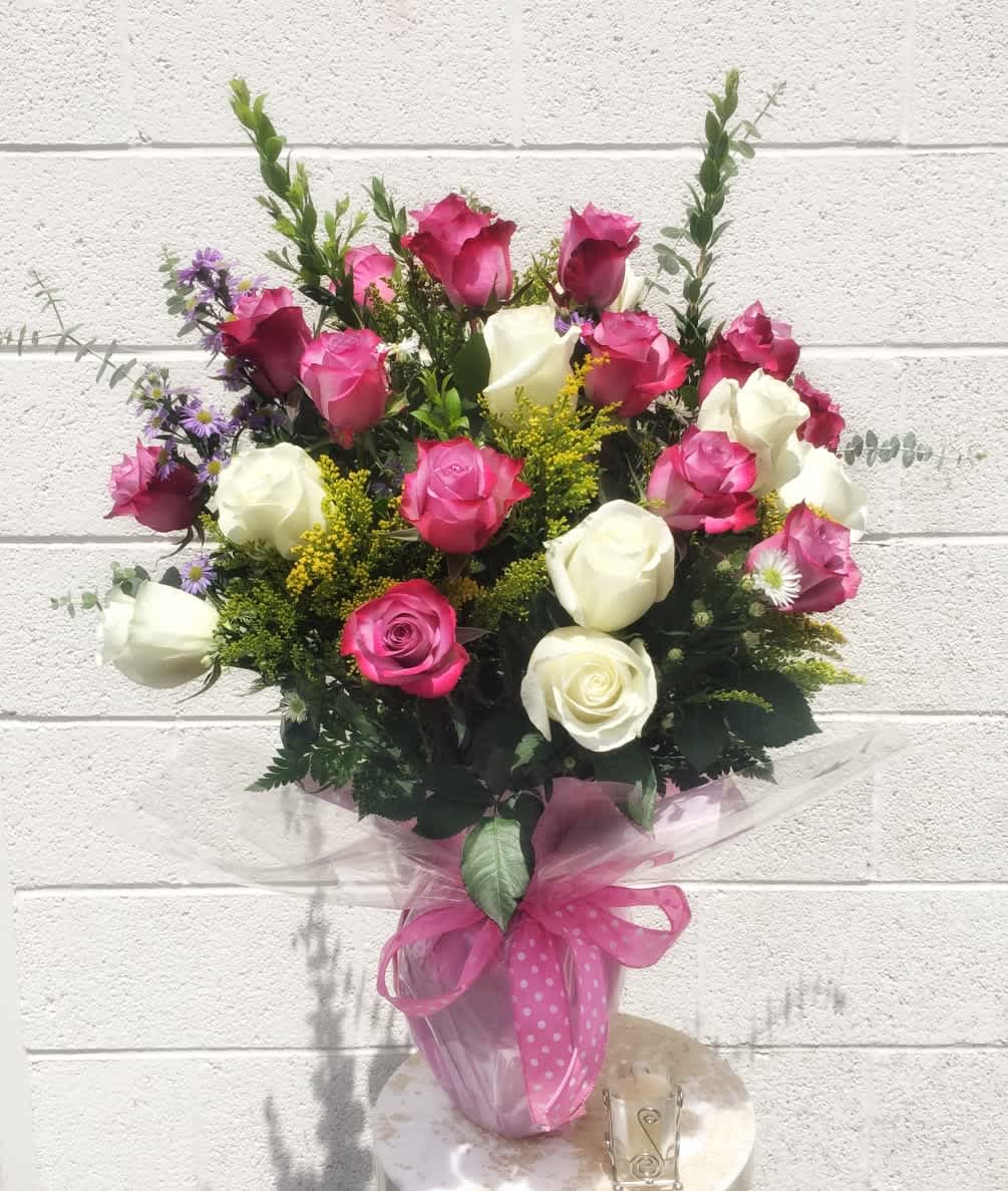 Bouquet of pink and white roses with small purple flowers in a wrapped vase