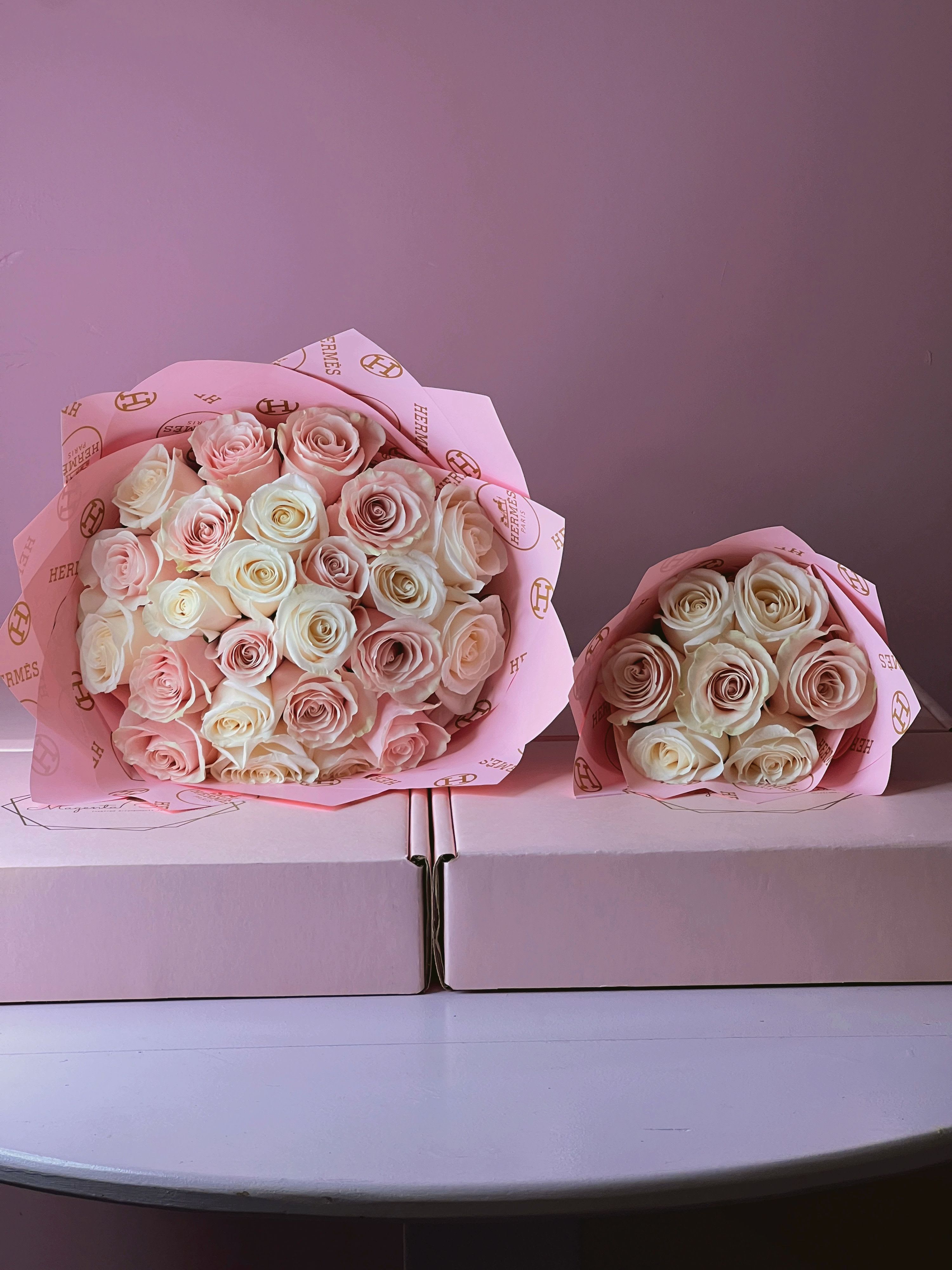 Two bouquets of pale pink and cream roses wrapped in pink paper
