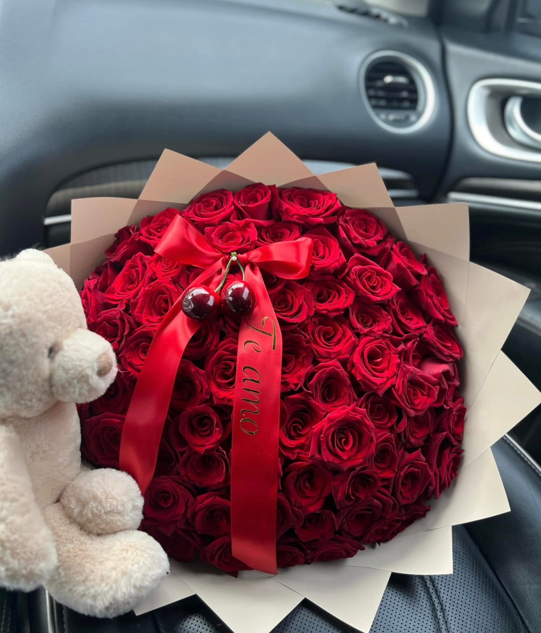 Round bouquet of red roses with a red ribbon and teddy bear