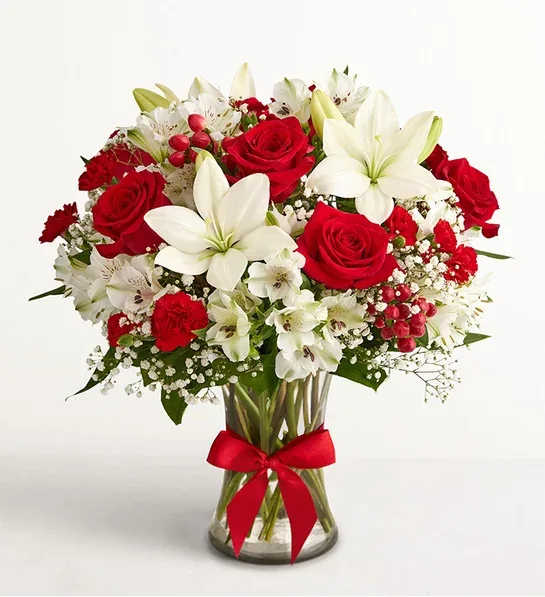 Bouquet of red roses and white lilies in a glass vase with a red ribbon