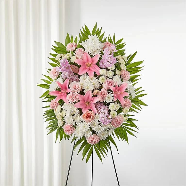 Standing floral wreath with pink and white flowers on a black easel