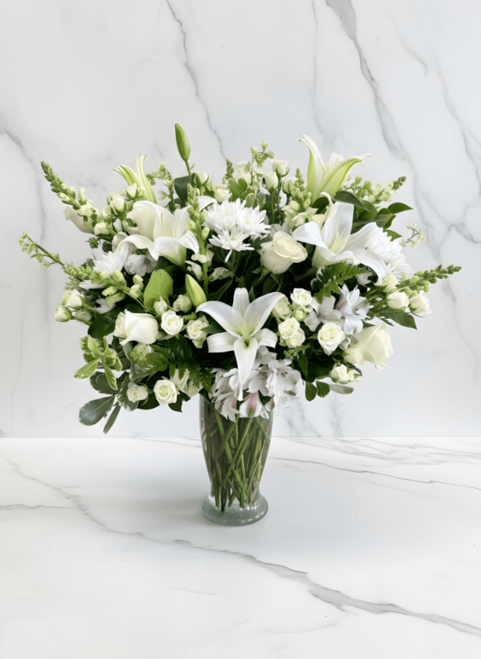 White lilies and roses arranged in a clear glass vase