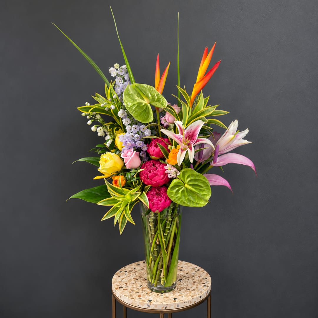 Tropical bouquet in a clear glass vase with pink, yellow, and white blooms