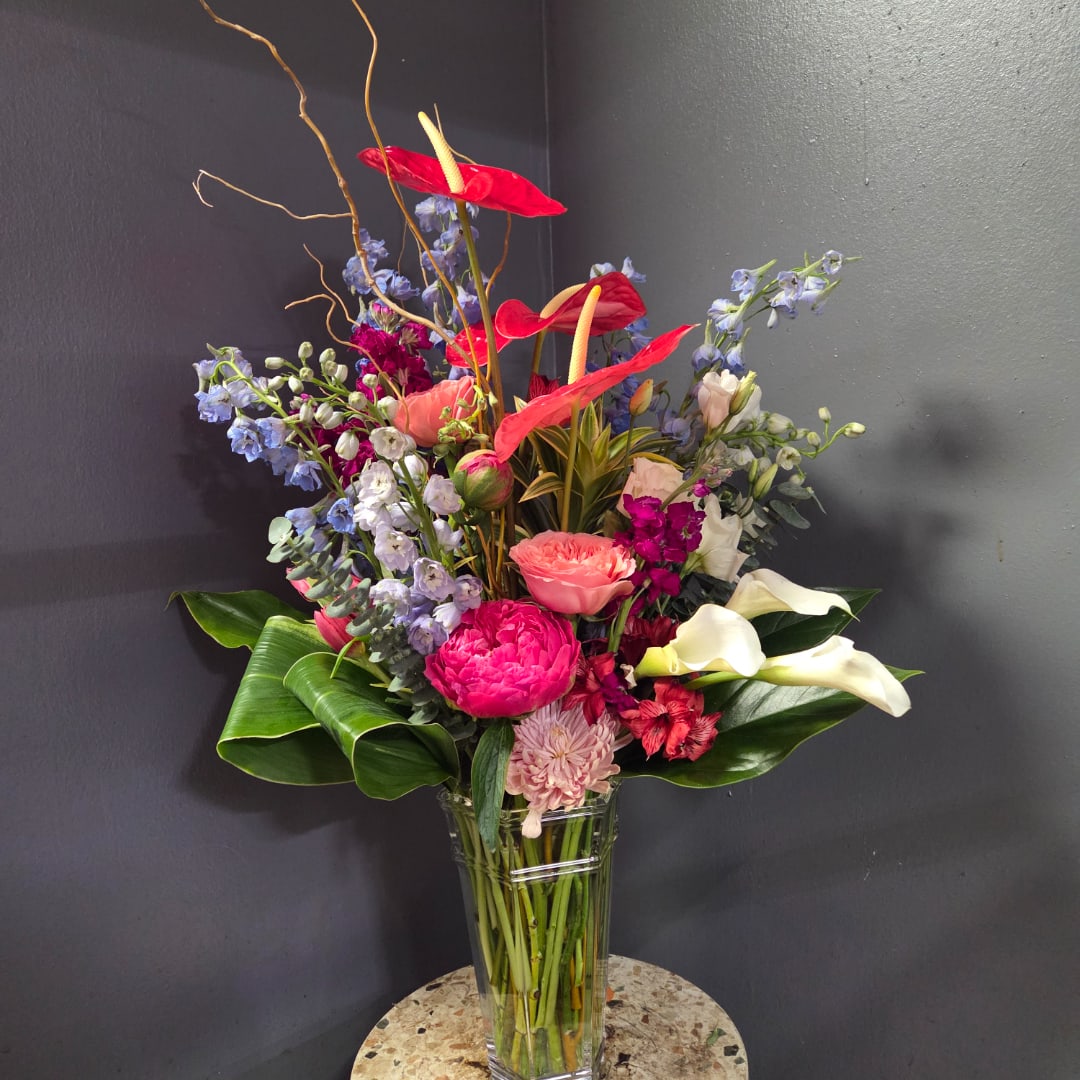 Tall mixed bouquet in a clear glass vase with red anthuriums and white calla lilies