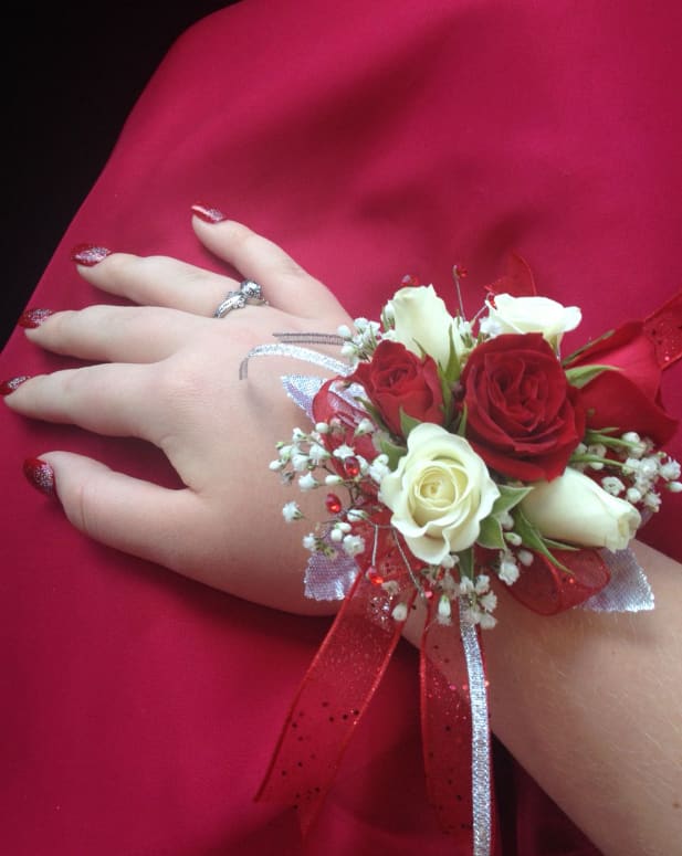 Red and white rose wrist corsage on a hand