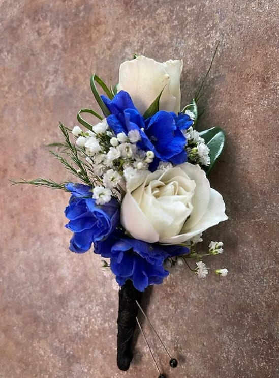 White and blue rose boutonniere with small white filler flowers