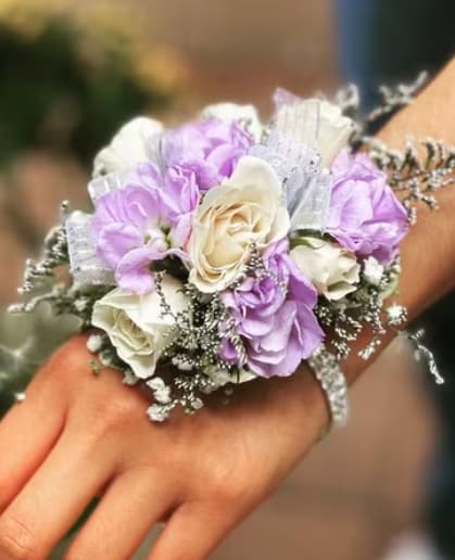 Wrist corsage with lavender and white roses on a hand