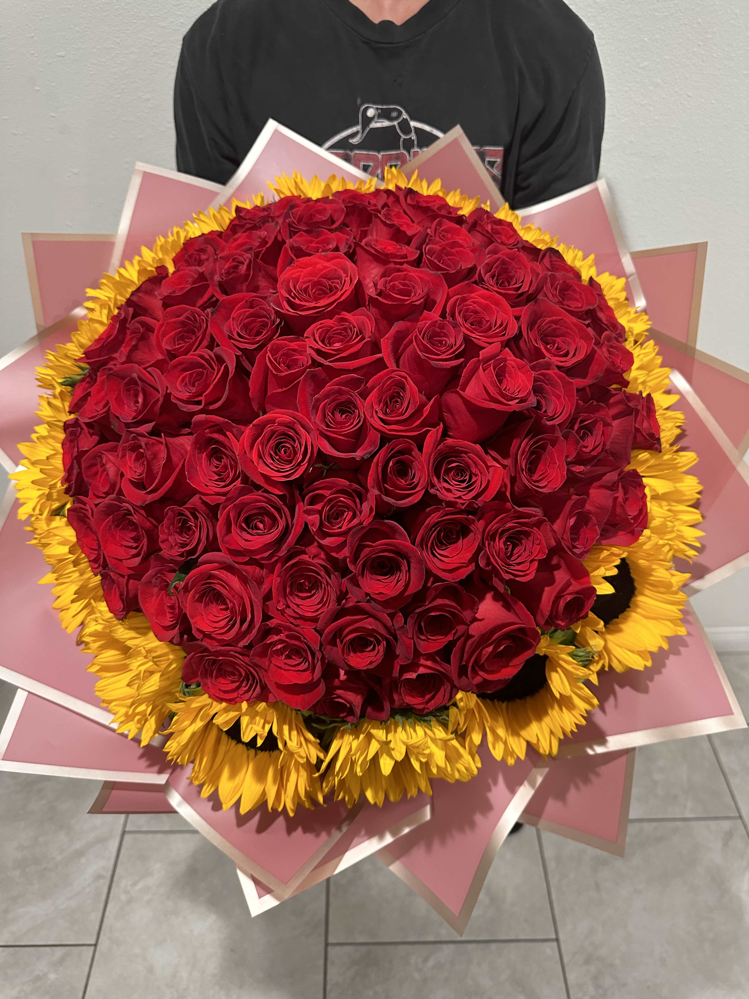 Large bouquet of red roses with a yellow sunflower border