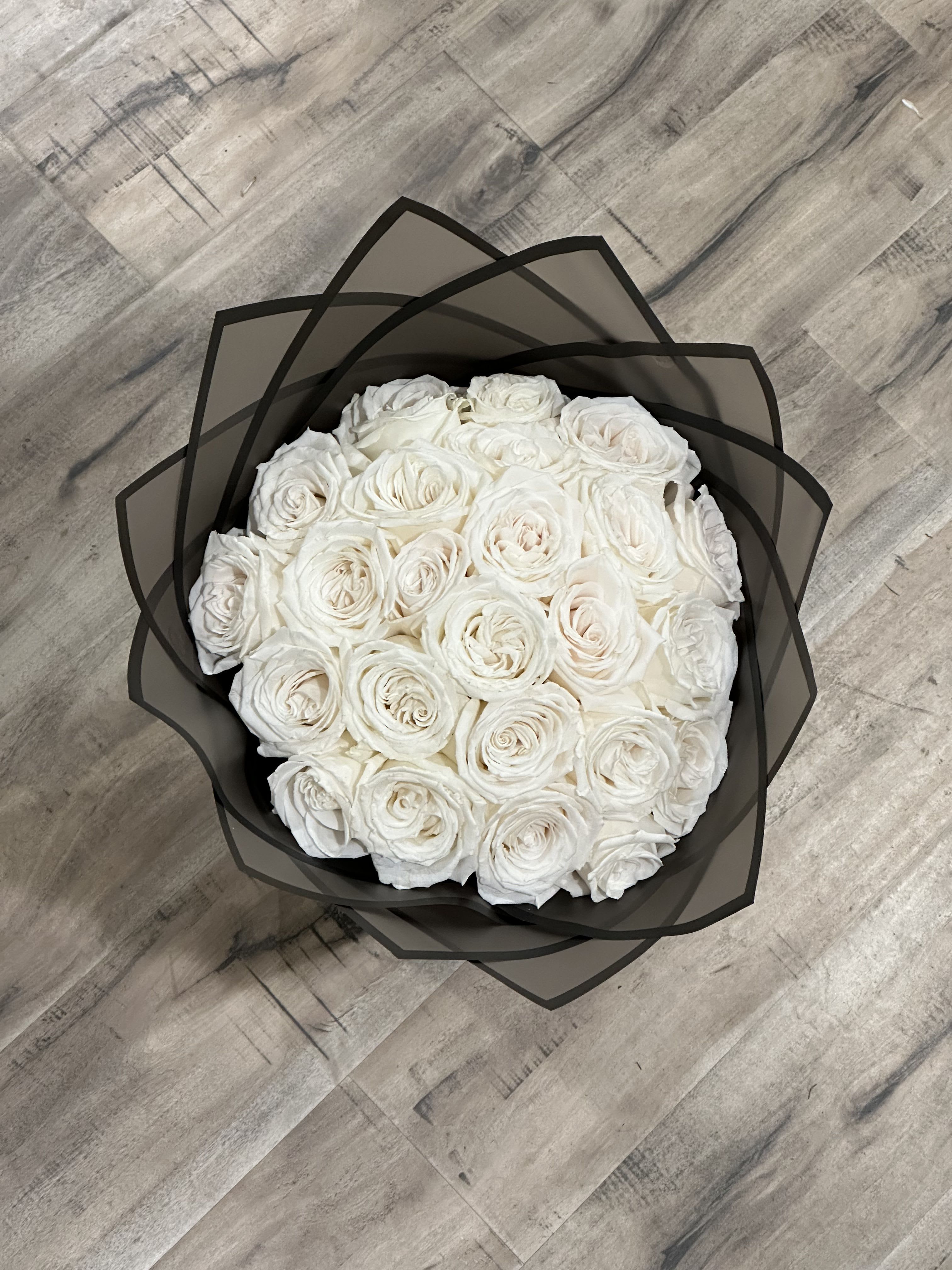 Round bouquet of white roses wrapped in black paper