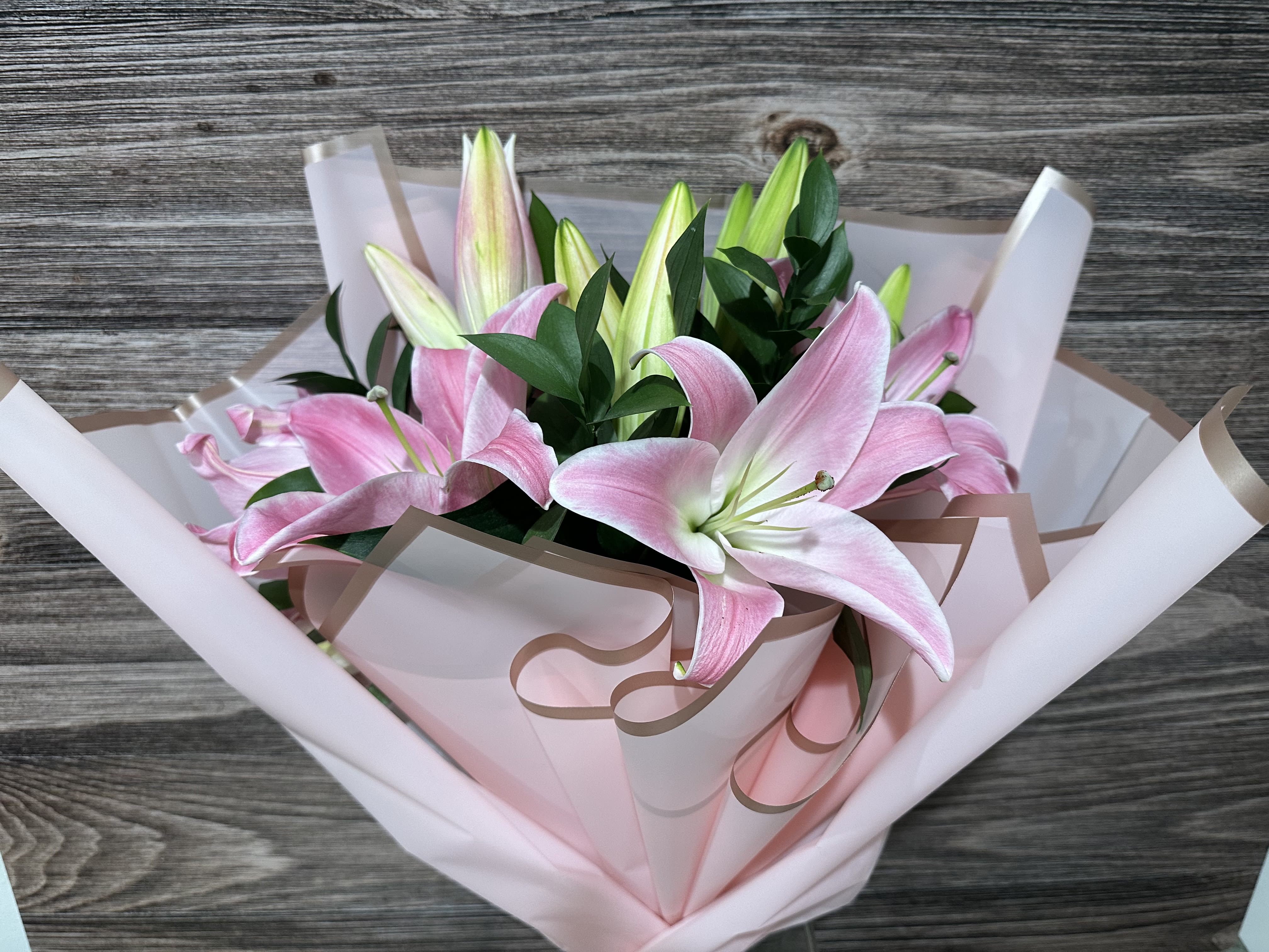 Bouquet of pink lilies wrapped in pale pink paper