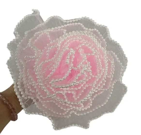 Pink beaded artificial rose held in a hand