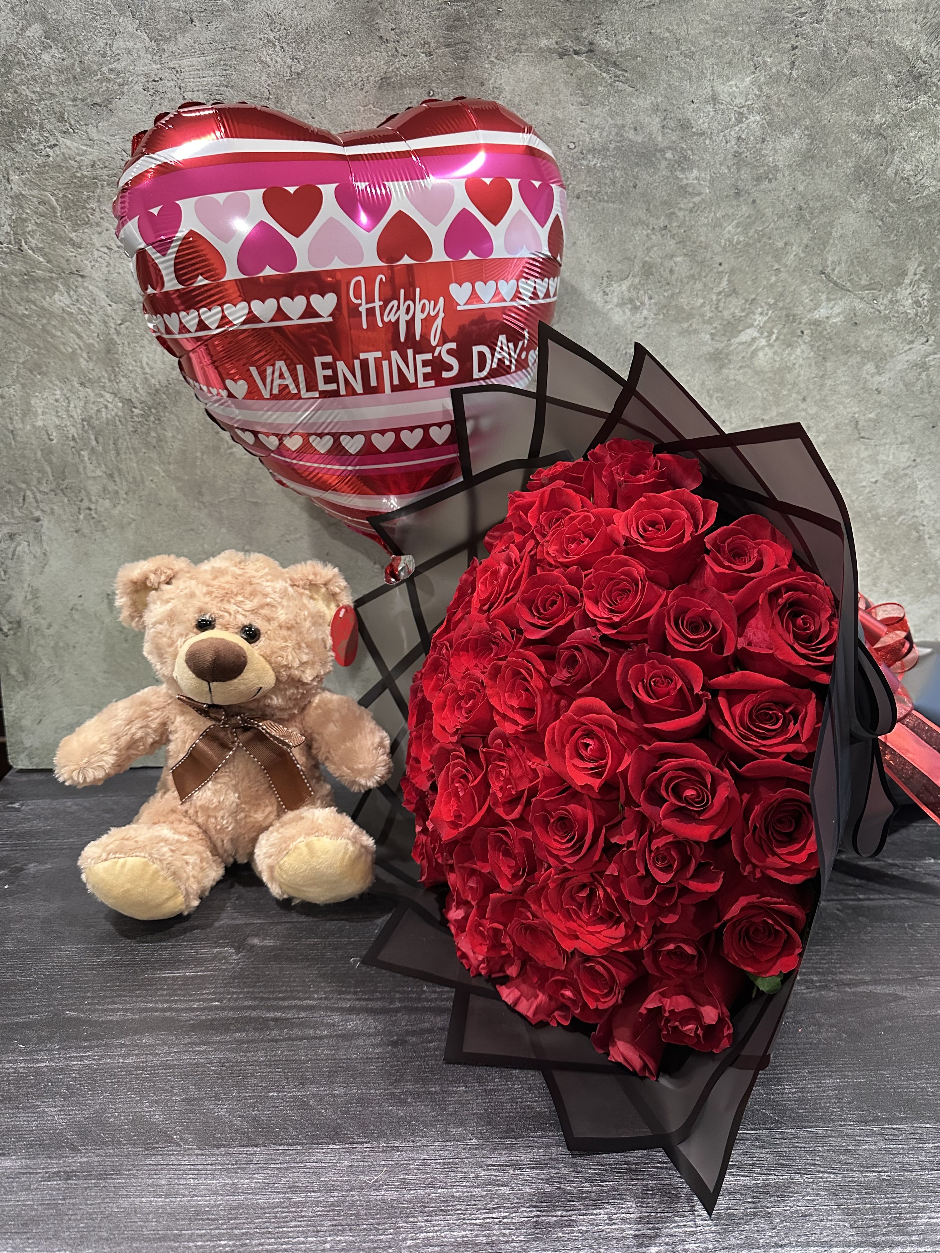 Red rose bouquet with a teddy bear and heart-shaped Valentine balloon