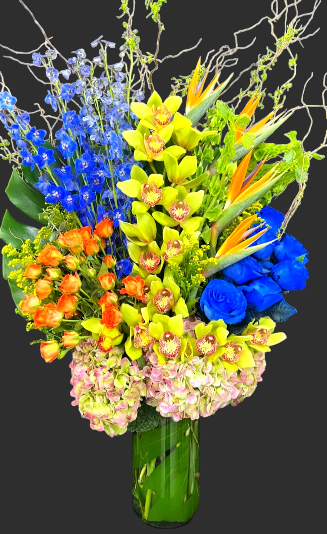 Colorful tropical bouquet in a tall glass vase with orchids and blue flowers