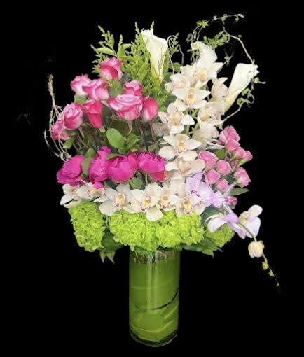 Pink roses and white orchids arranged in a tall glass vase