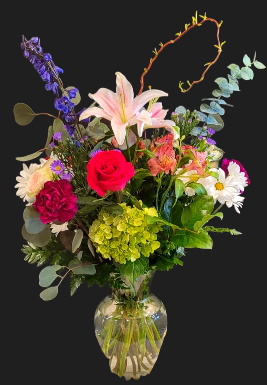 Mixed bouquet with a pink lily, red rose, and daisies in a glass vase