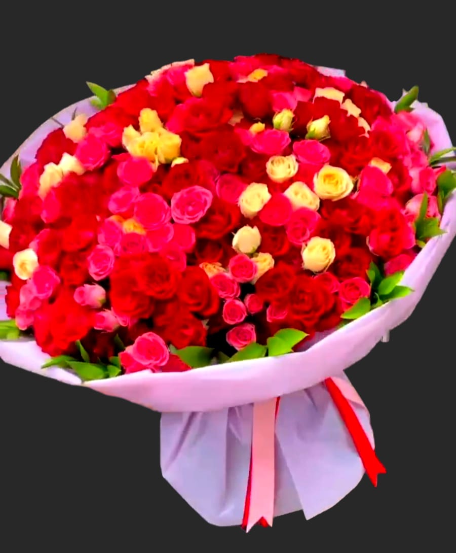 Large bouquet of red, pink, and yellow roses wrapped in white paper