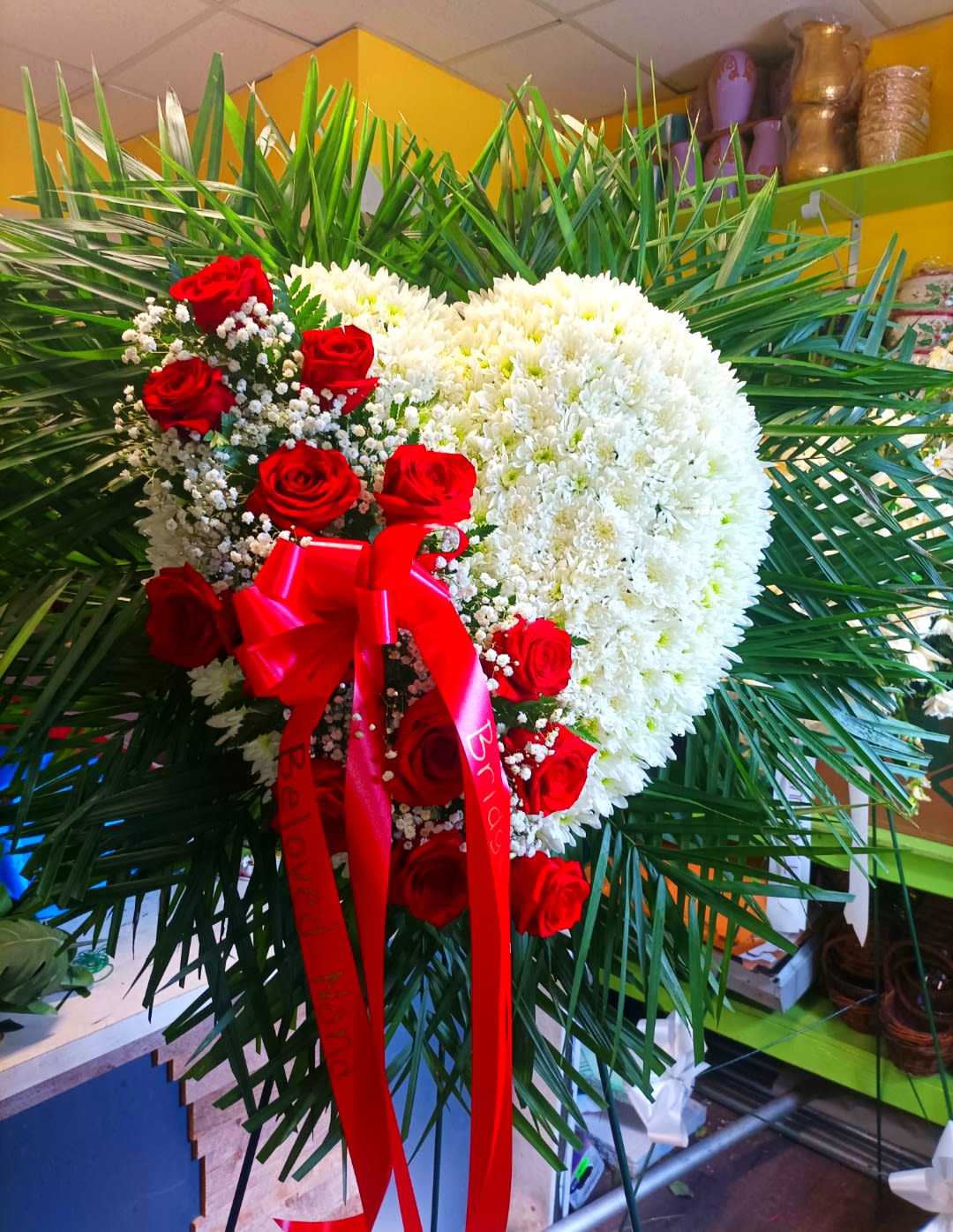 Heart-shaped white chrysanthemum arrangement with red roses and ribbon