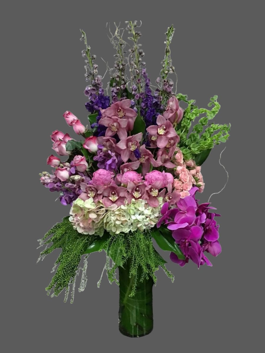 Tall bouquet of pink and purple flowers in a green vase