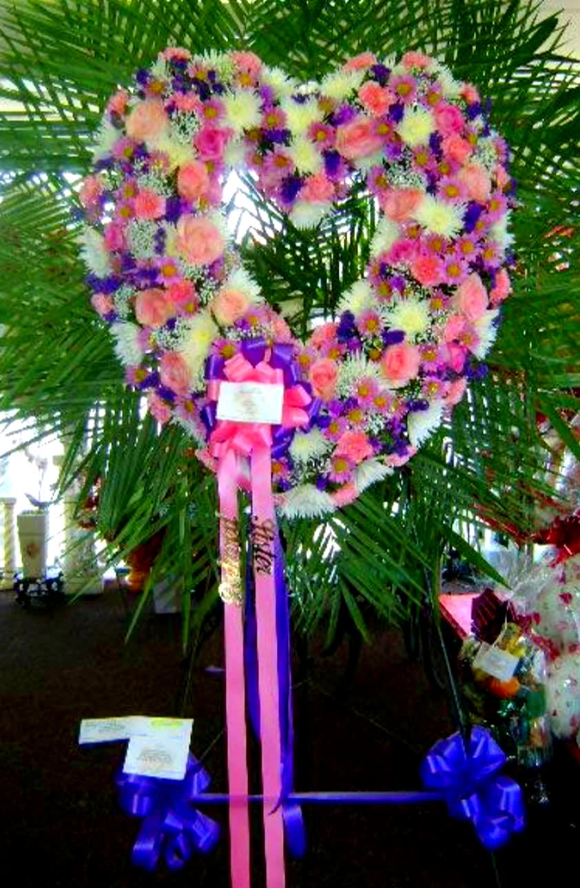 Heart-shaped floral wreath with pink, white, and purple flowers on a stand