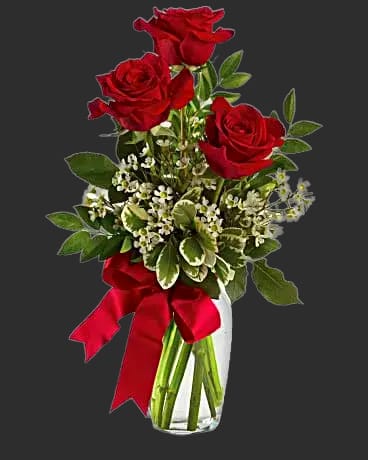 Red roses in a clear glass vase with a red ribbon