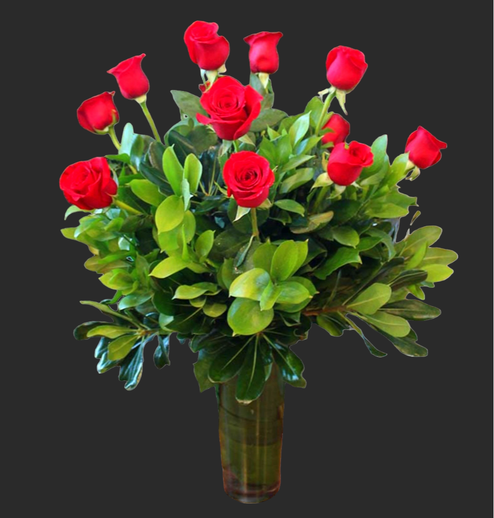 Red roses arranged in a clear glass vase with dense greenery
