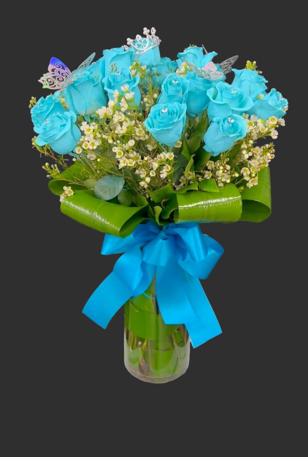 Blue roses in a glass vase with a bright ribbon bow