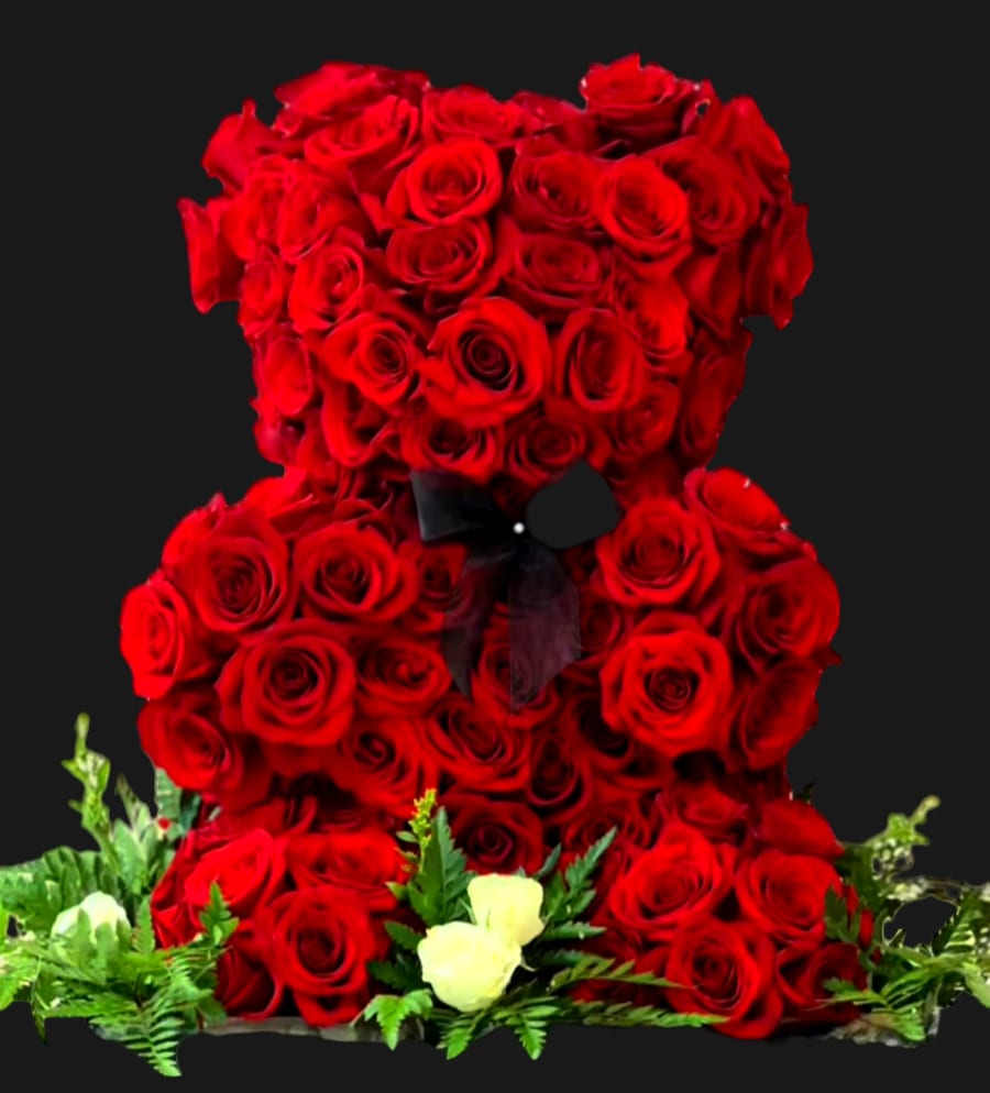 Red rose teddy bear with a black ribbon and small white roses at the base