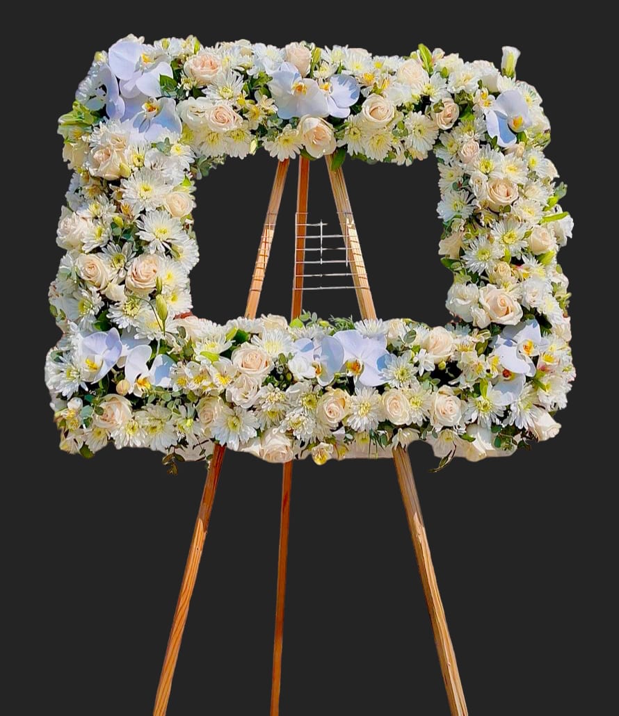Square floral wreath on a wooden easel with white and blush flowers