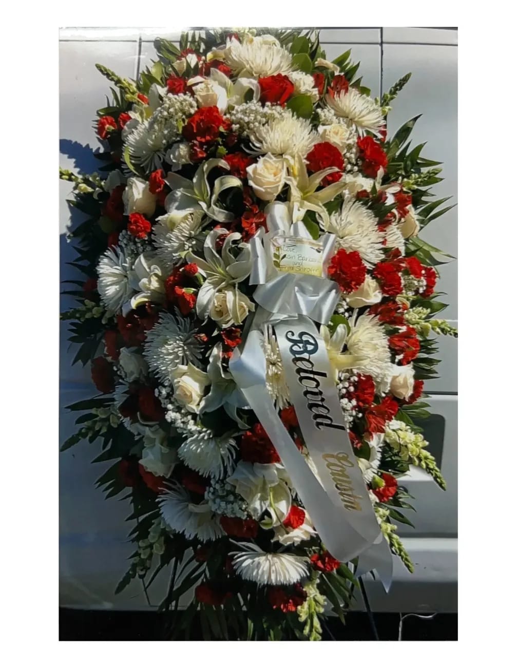 Large red and white funeral spray with ribbon on an easel