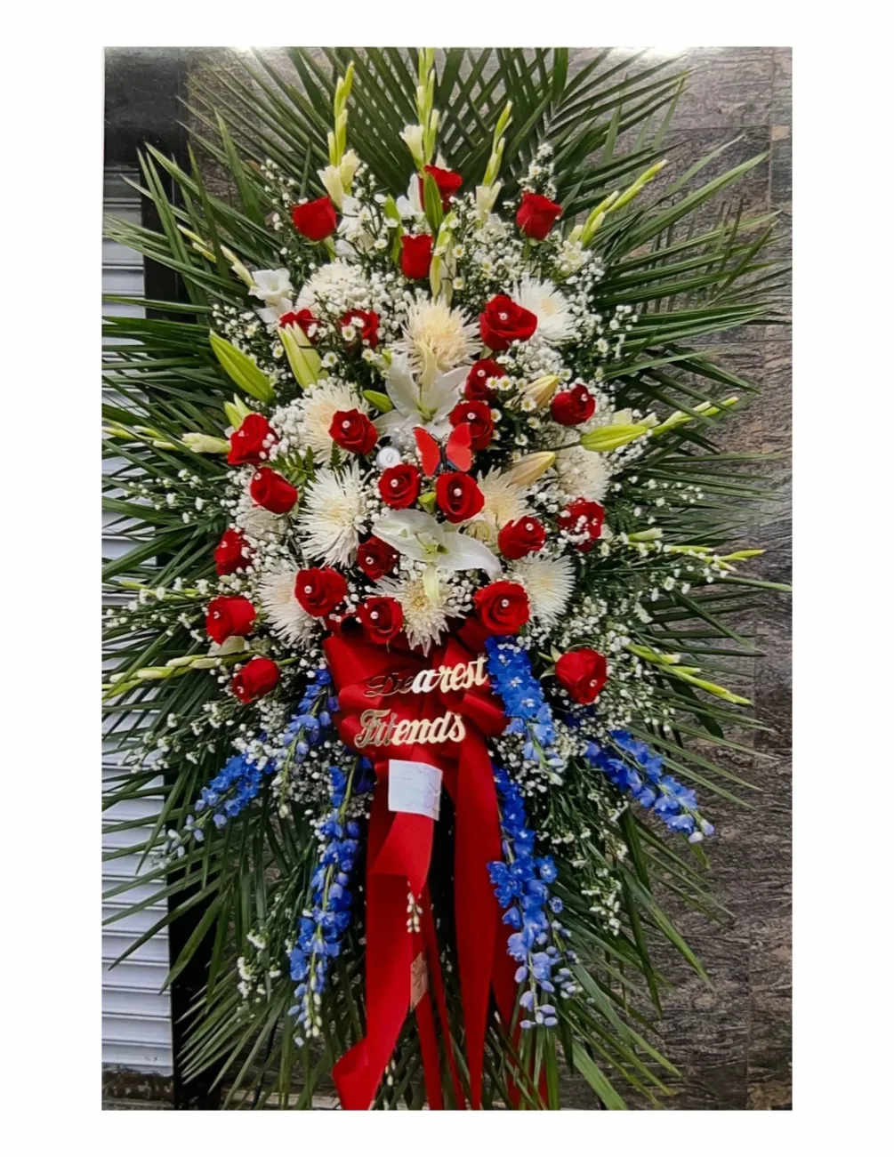 Standing floral spray with red and white flowers and blue accents
