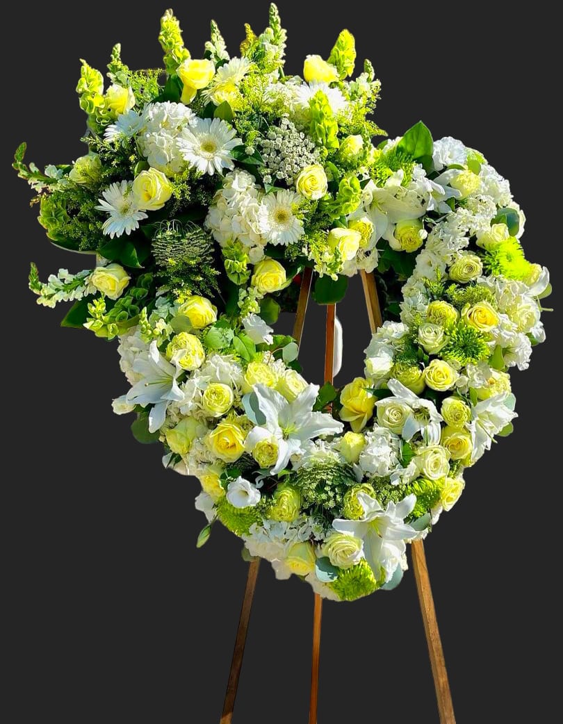 Heart-shaped floral wreath of white and yellow flowers on an easel