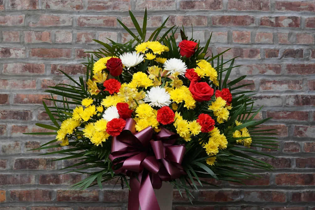 Red roses and yellow-white chrysanthemums in a vase with a purple ribbon