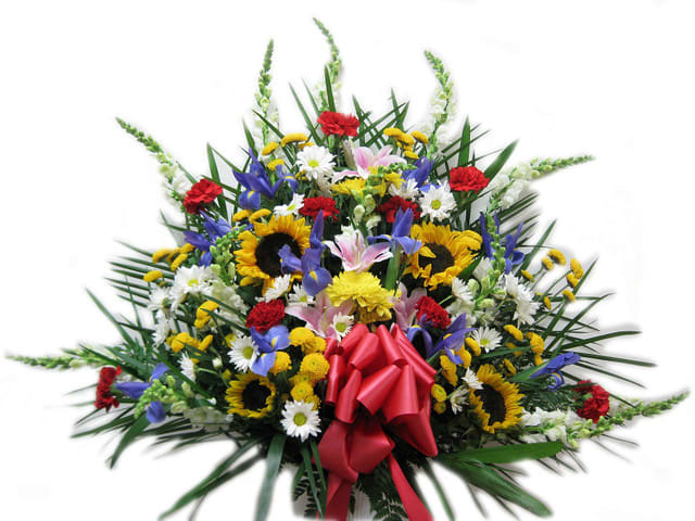 Large mixed floral spray with sunflowers, daisies, and a red bow