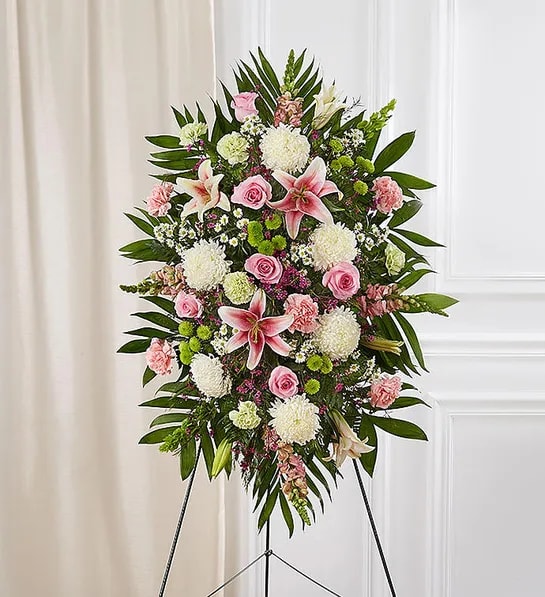 Standing floral spray with pink lilies, roses, and white mums on an easel
