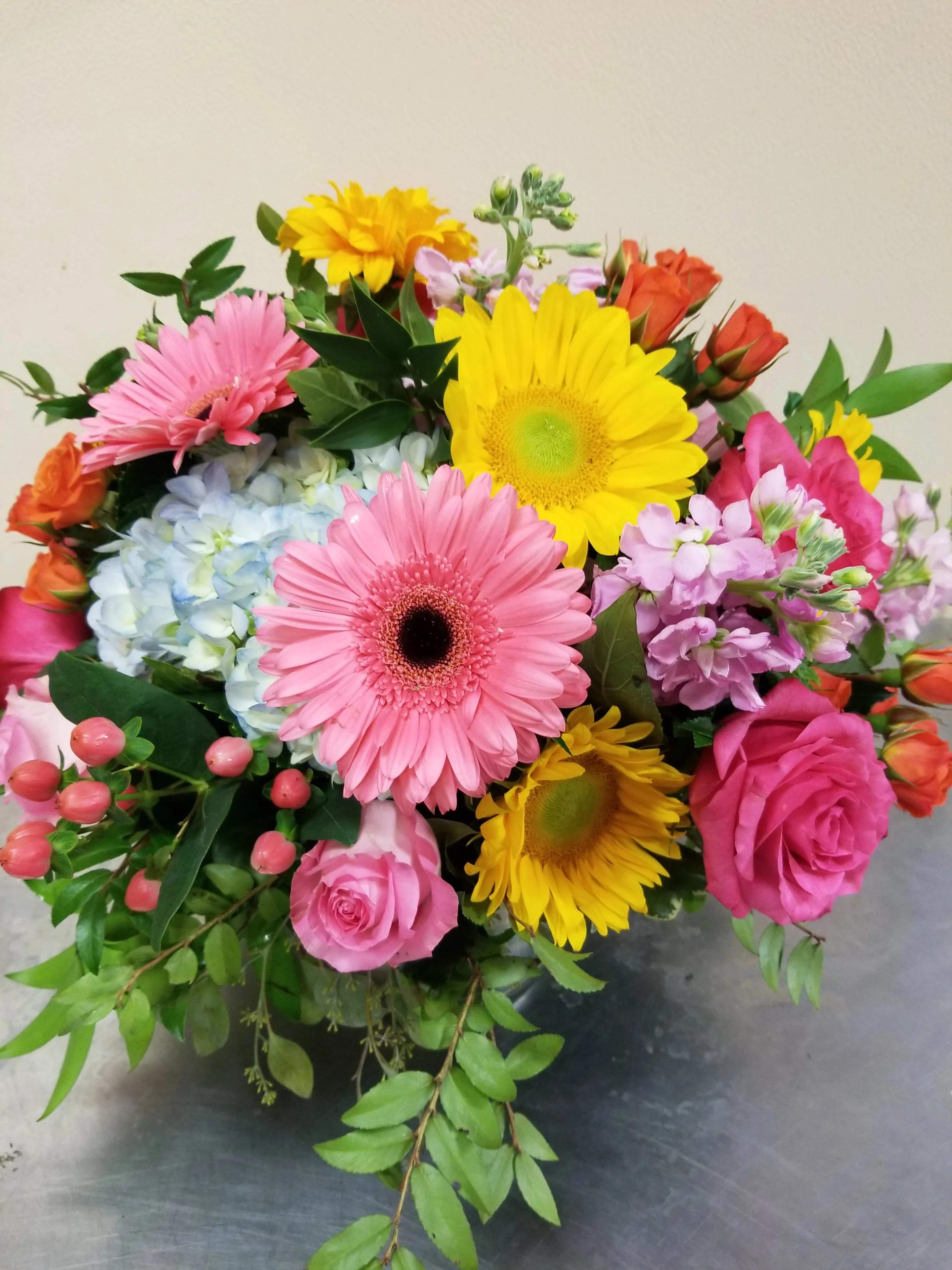 Mixed bouquet with pink gerbera daisies, yellow daisies, roses, and hydrangea