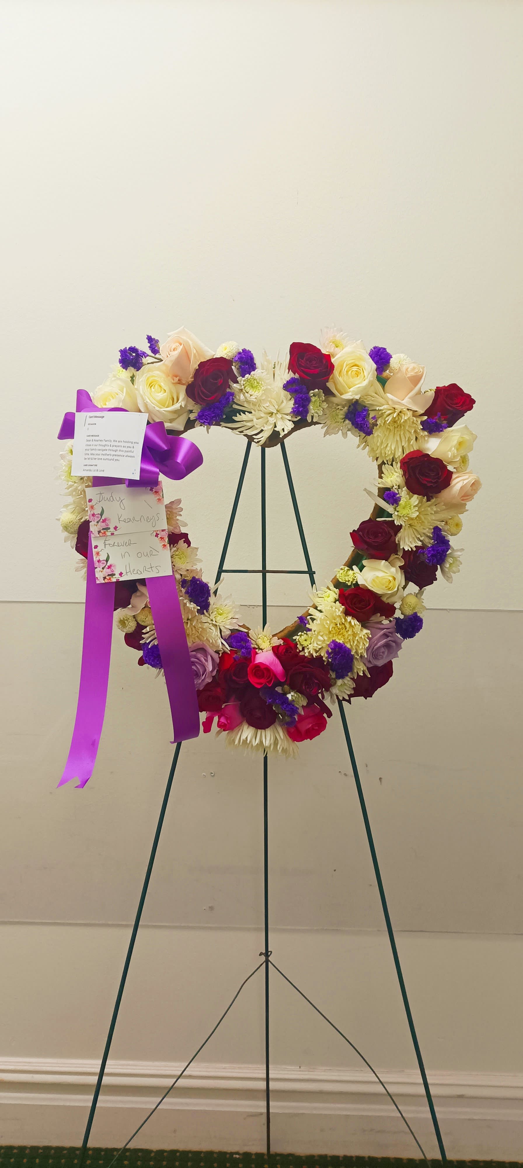 Heart-shaped floral wreath on a stand with roses and chrysanthemums