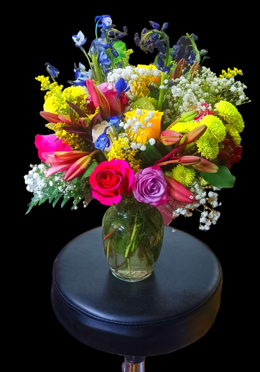 Colorful mixed bouquet in a glass vase on a stool
