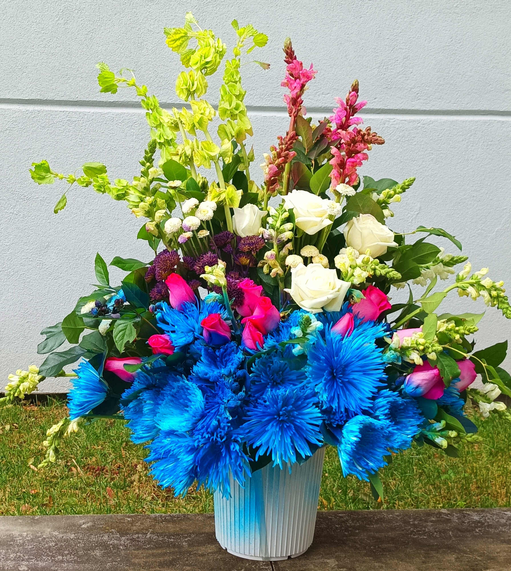 Bright mixed bouquet in a blue vase with blue, pink, white, and green flowers