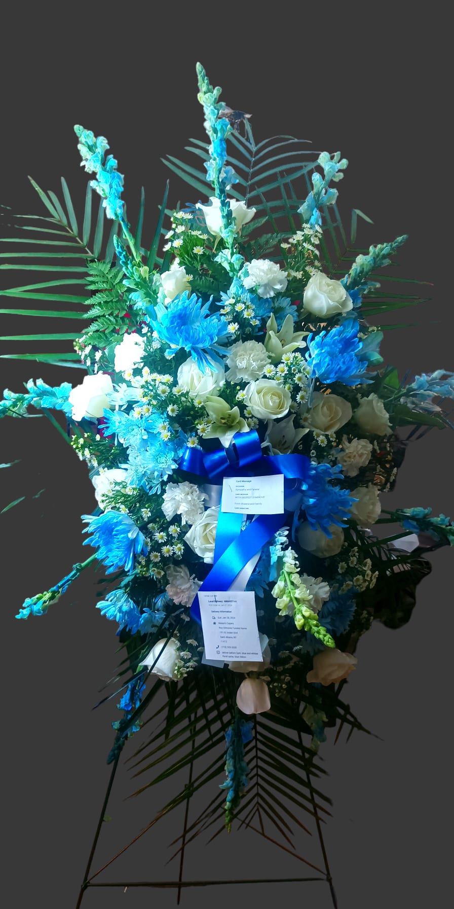 Tall blue and white floral standing spray on an easel with ribbon
