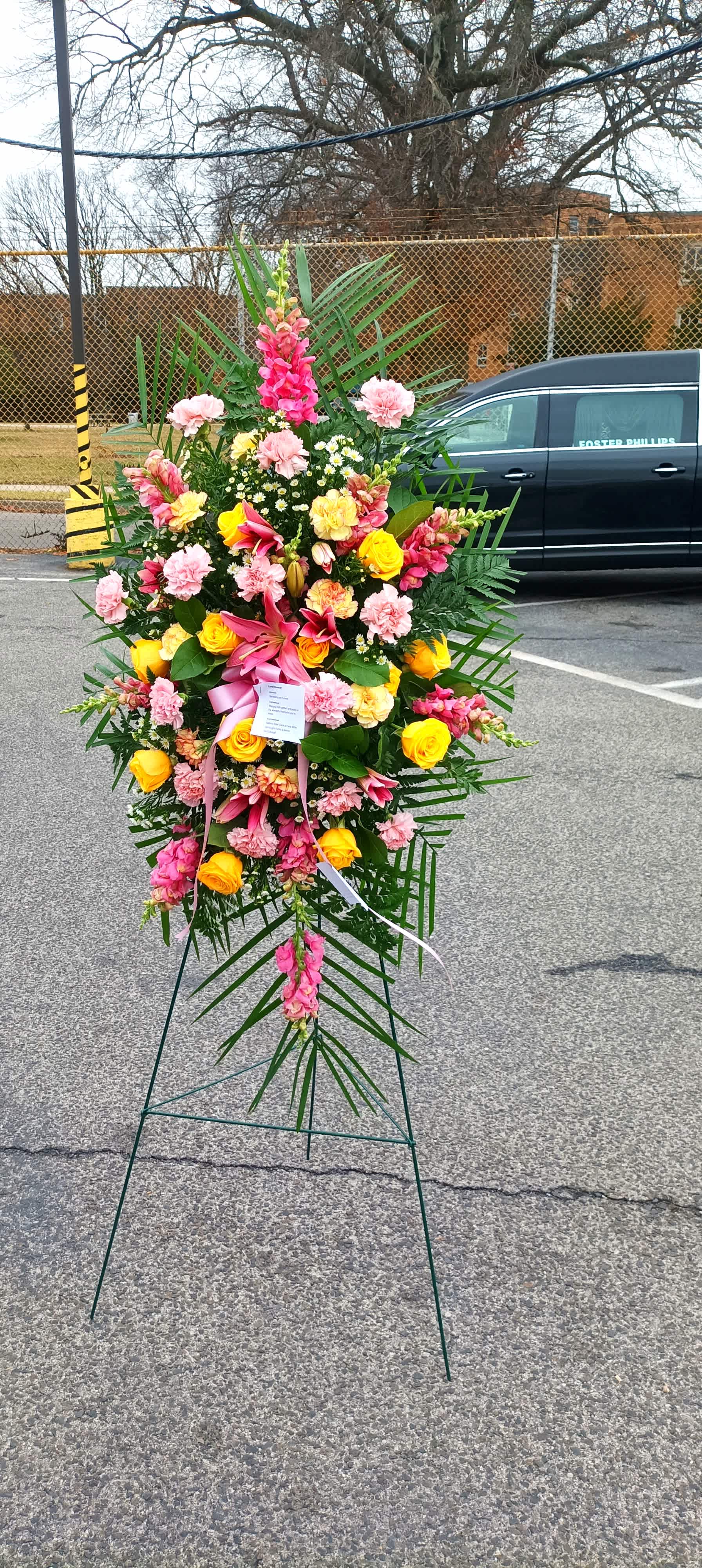 Standing floral spray with pink, yellow, and white flowers on an easel